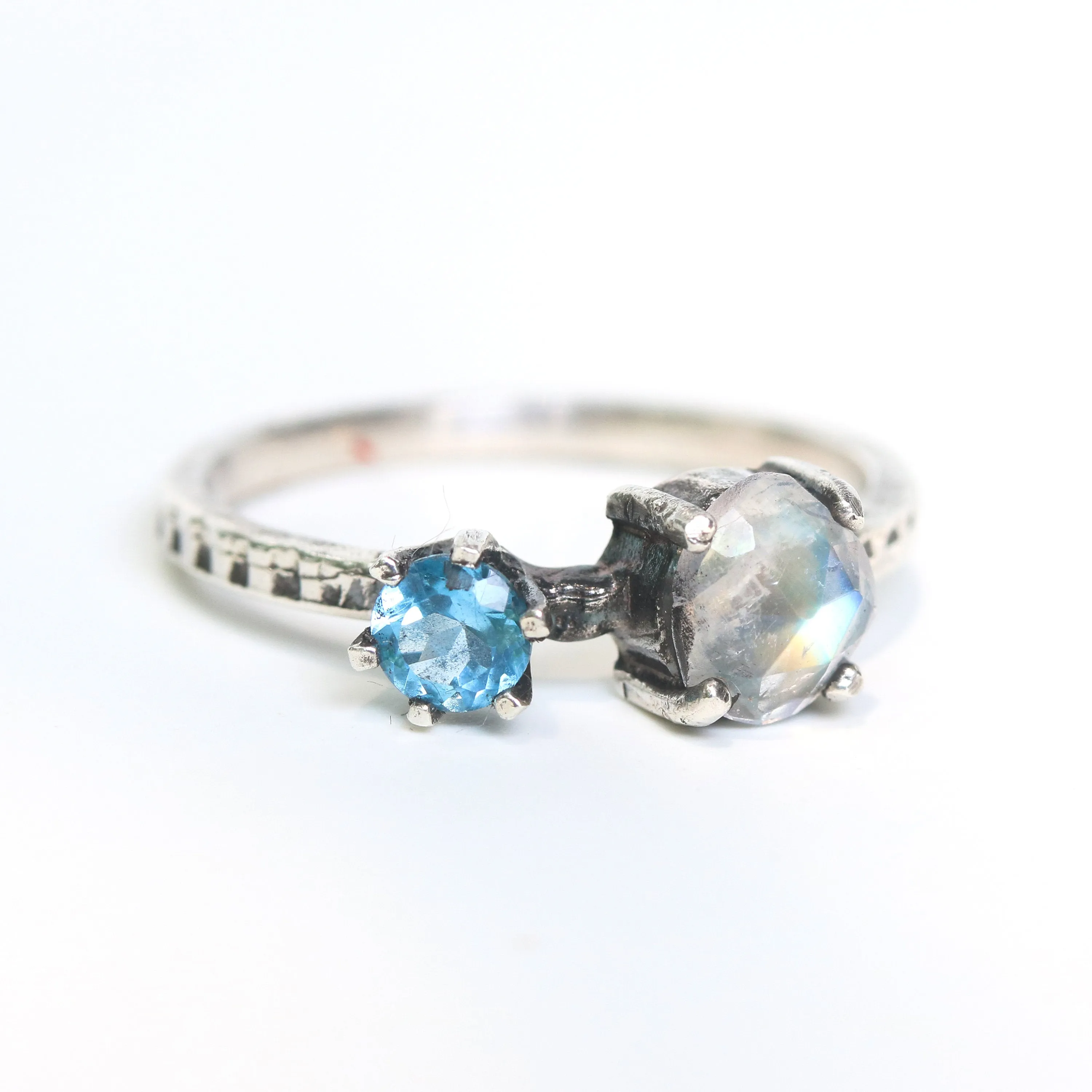 Faceted moonstone ring in silver bezel setting and blue topaz on the side with sterling silver band