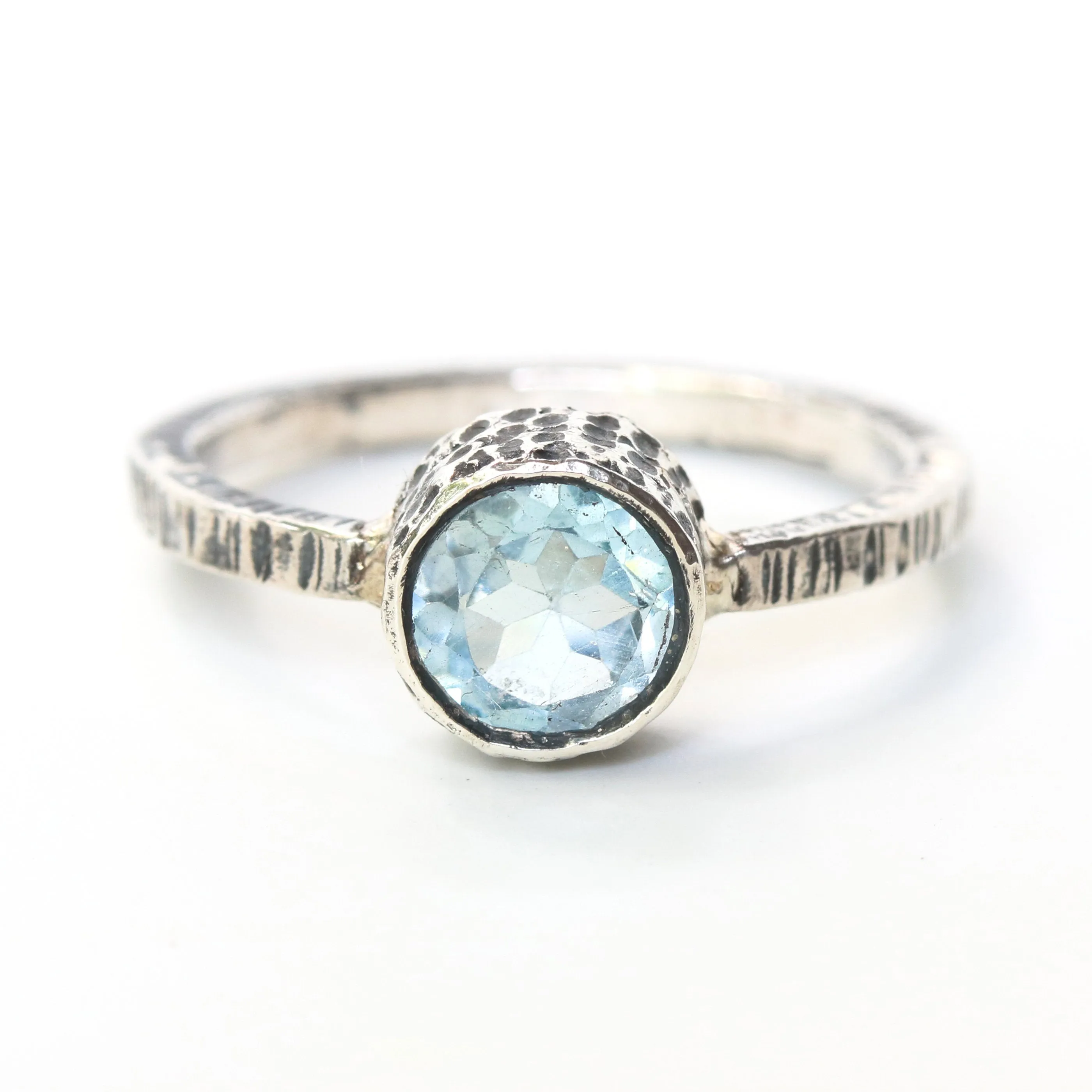 Round faceted blue topaz ring in silver bezel setting with sterling silver texture design band
