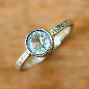 Round faceted blue topaz ring in silver bezel setting with sterling silver texture design band