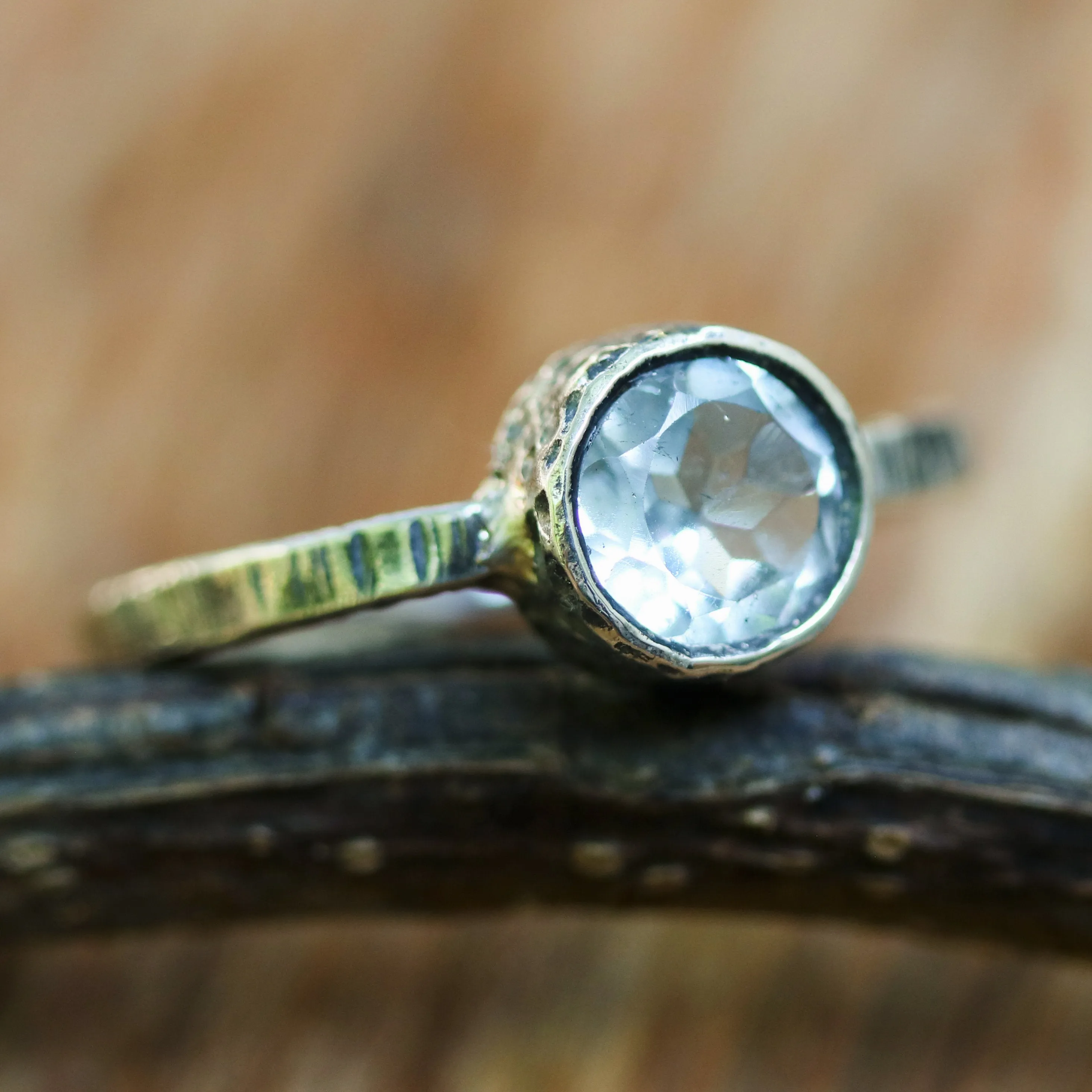 Round faceted blue topaz ring in silver bezel setting with sterling silver texture design band