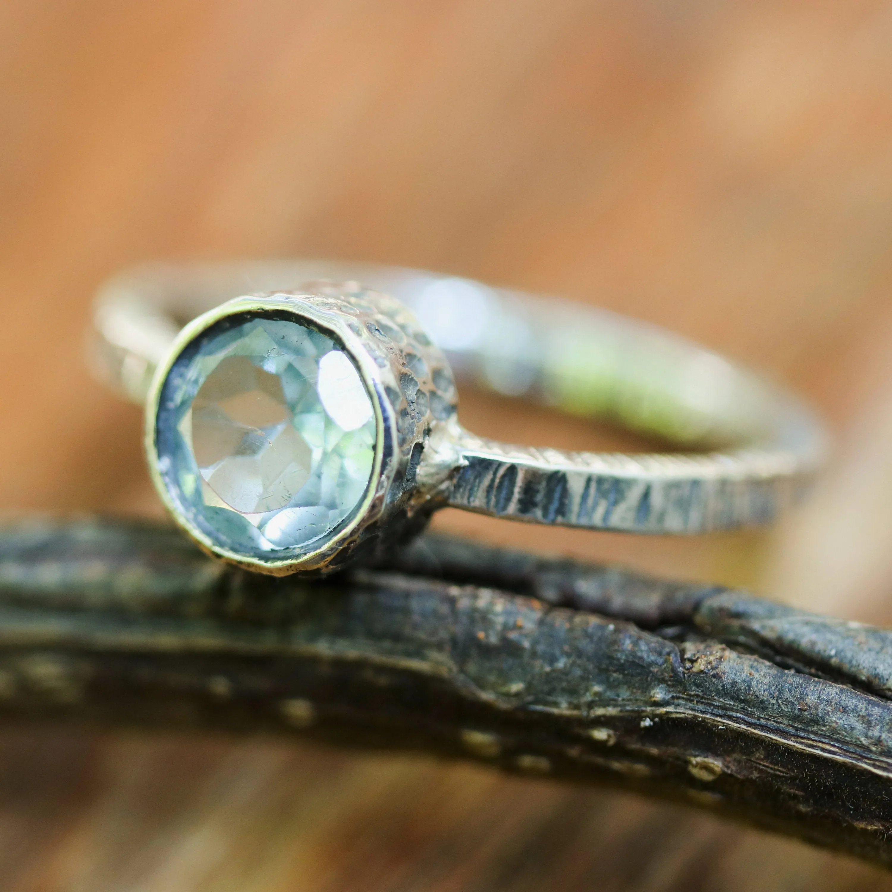 Round faceted blue topaz ring in silver bezel setting with sterling silver texture design band