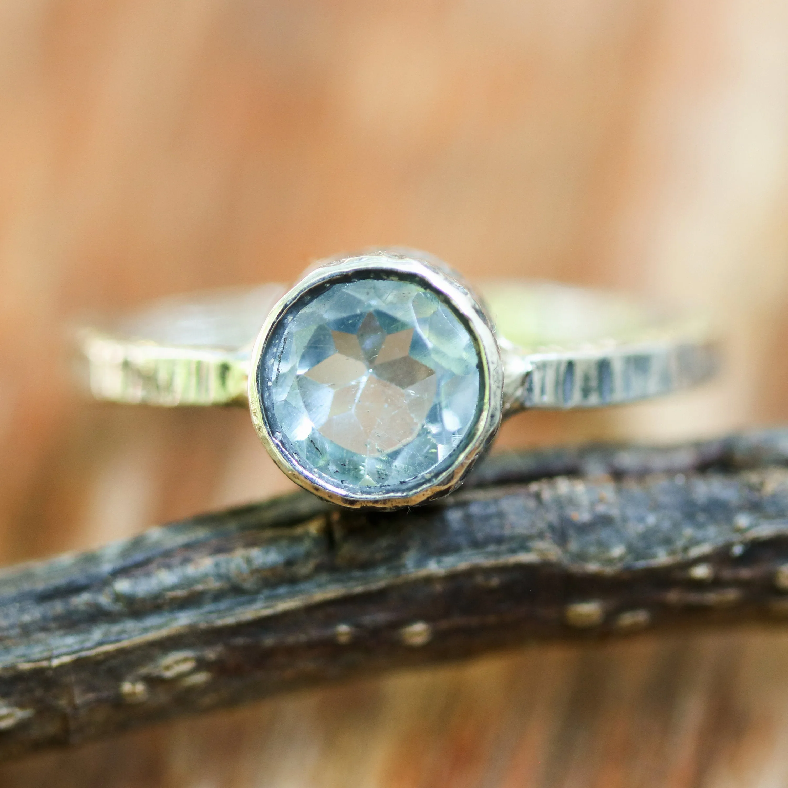 Round faceted blue topaz ring in silver bezel setting with sterling silver texture design band